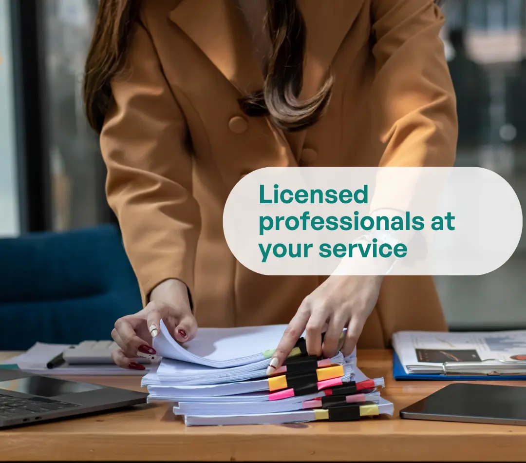 Hands organizing a stack of flagged documents on a desk; text overlay reads ‘Licensed professionals at your service’.