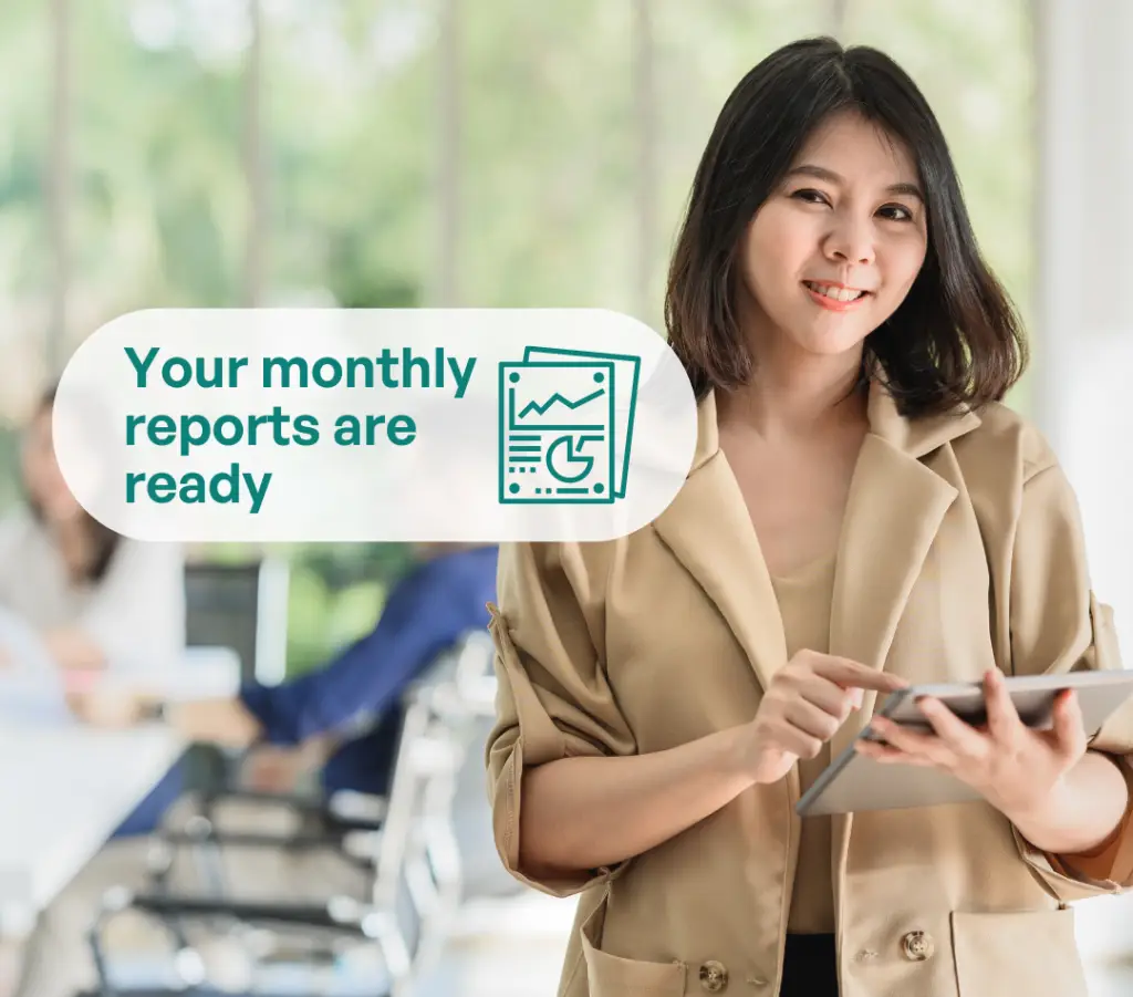 Smiling businesswoman using tablet with text overlay: Your monthly reports are ready – professional accounting and bookkeeping services.