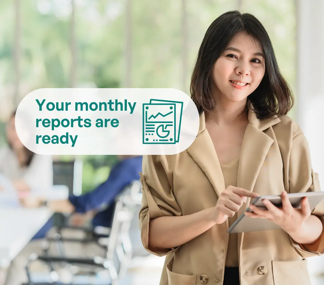 Smiling businesswoman using tablet with text overlay: Your monthly reports are ready – professional accounting and bookkeeping services.